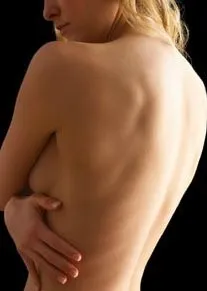 Photo of a woman's bare back with hands covering the breast